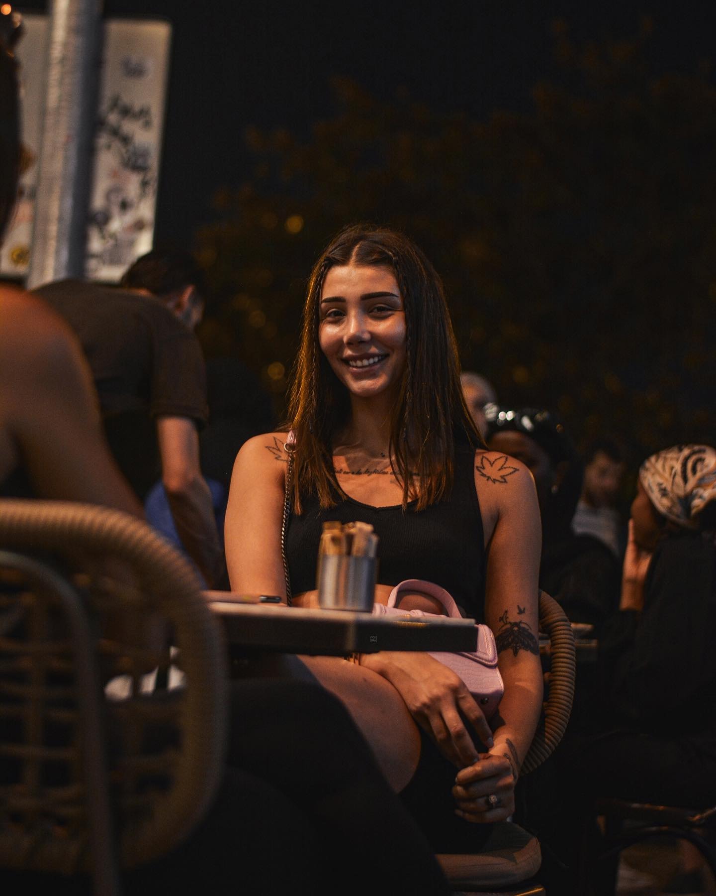 Woman with braided strands of hair smiling at an outdoor café table at night